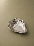 Studio Boy Shell stainless steel serving plate with a polished finish and seashell shape on a neutral background.